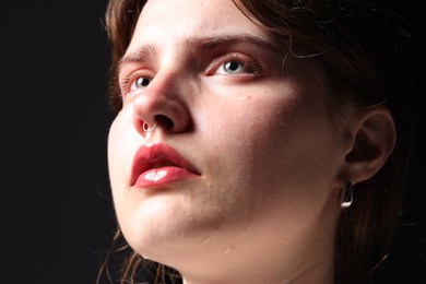 Photo of Sad woman crying on black background, closeup