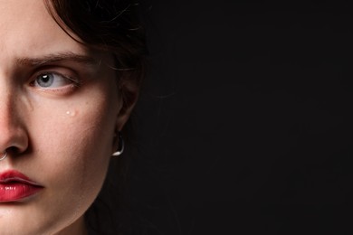 Photo of Sad woman crying on black background, closeup