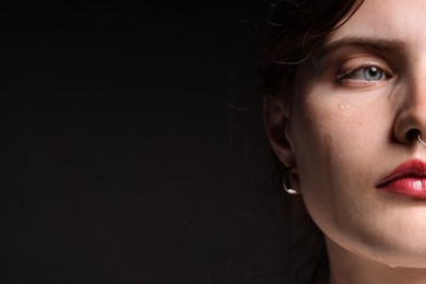 Photo of Sad woman crying on black background, closeup