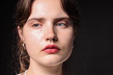Photo of Sad woman crying on black background, closeup