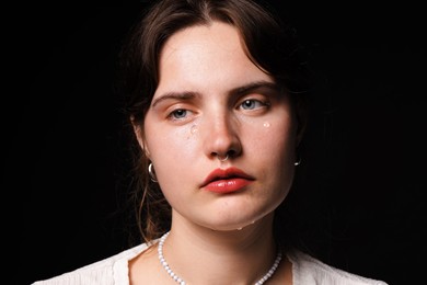 Photo of Sad young woman crying on black background