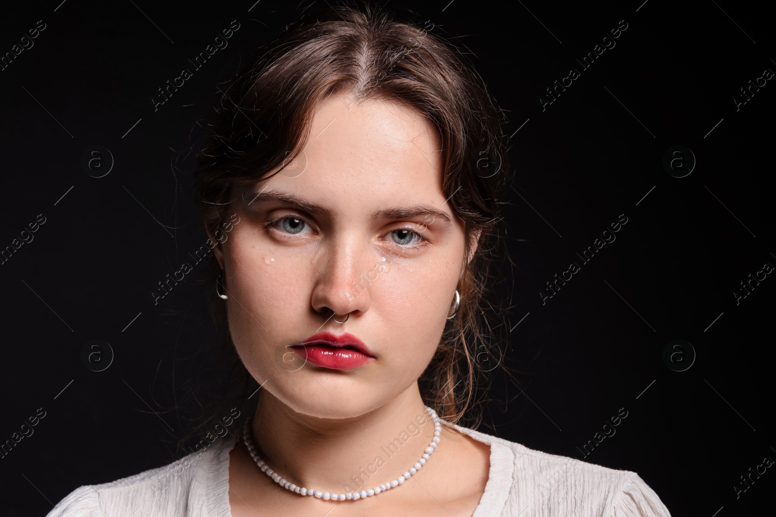 Photo of Sad young woman crying on black background