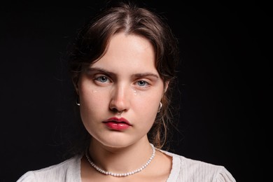 Photo of Sad young woman crying on black background