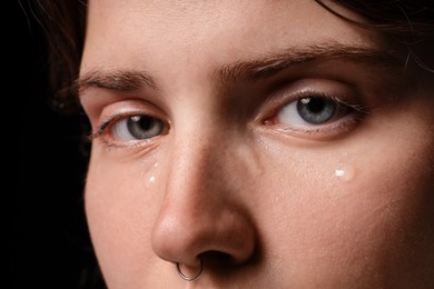 Photo of Sad woman crying on black background, closeup