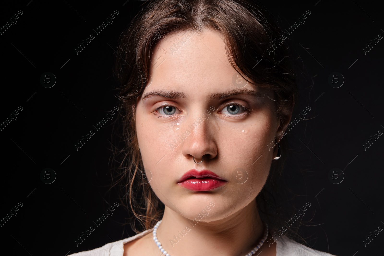 Photo of Sad young woman crying on black background