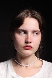Photo of Sad young woman crying on black background
