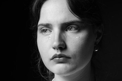 Photo of Sad woman crying on dark background, closeup. Black and white effect
