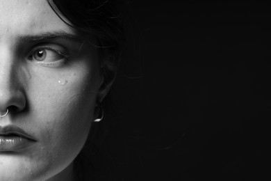 Photo of Sad woman crying on dark background, closeup. Black and white effect