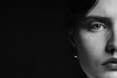 Photo of Sad woman crying on dark background, closeup. Black and white effect