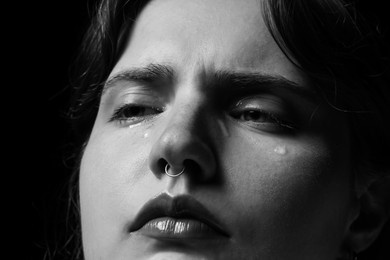 Photo of Sad woman crying on dark background, closeup. Black and white effect