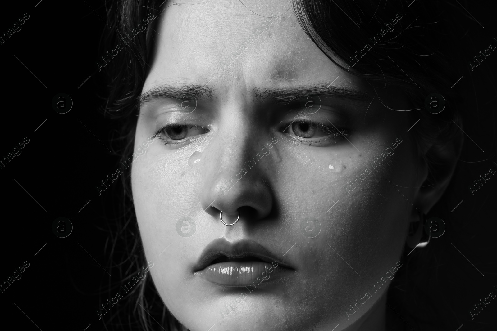 Photo of Sad woman crying on dark background, closeup. Black and white effect