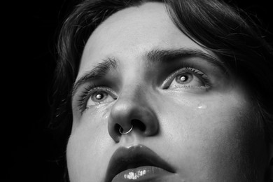 Photo of Sad woman crying on dark background, closeup. Black and white effect