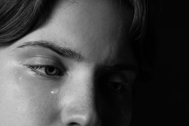 Photo of Sad woman crying on dark background, closeup. Black and white effect