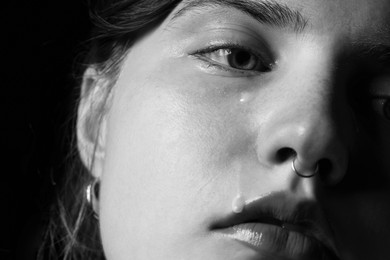 Photo of Sad woman crying on dark background, closeup. Black and white effect