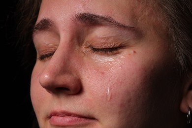 Photo of Sad woman crying on black background, closeup