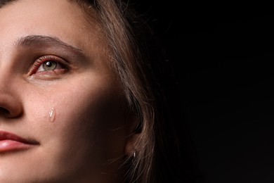 Photo of Sad woman crying on black background, closeup