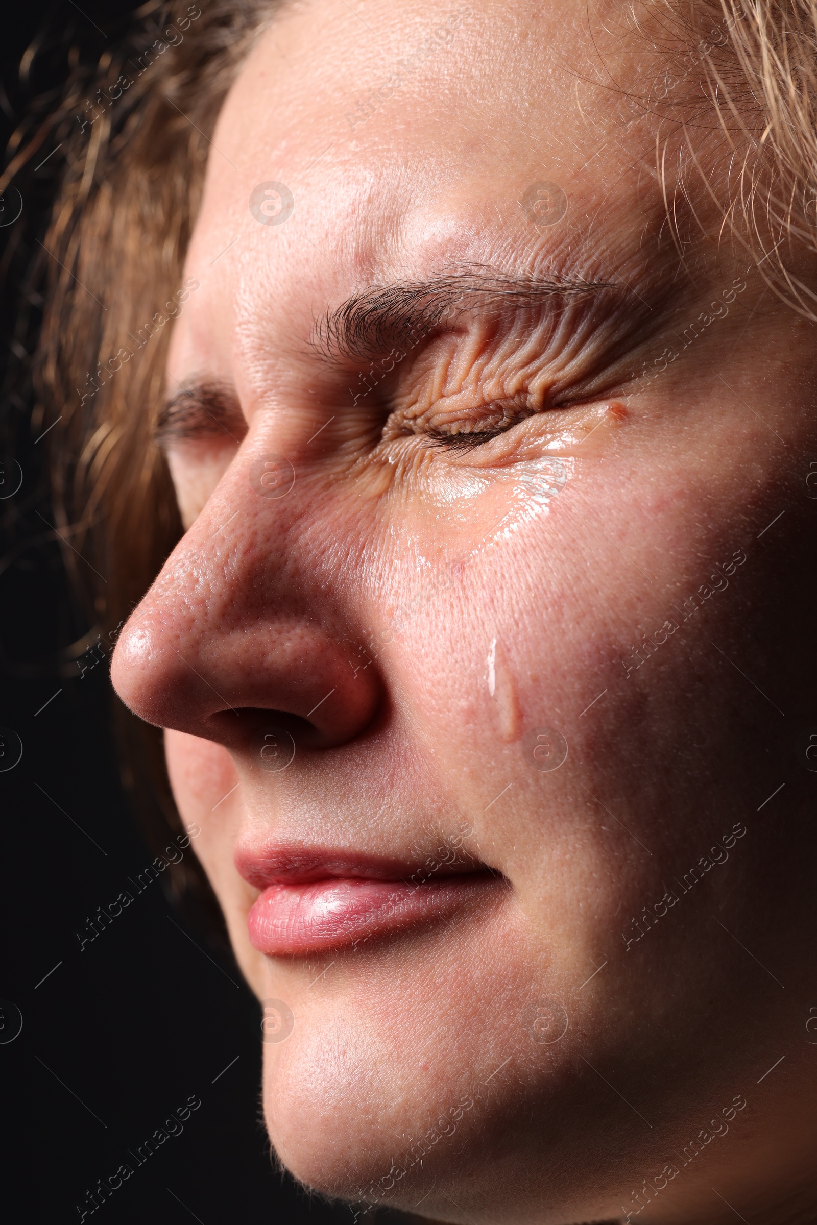 Photo of Sad woman crying on black background, closeup