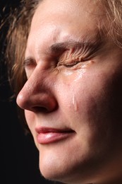 Photo of Sad woman crying on black background, closeup