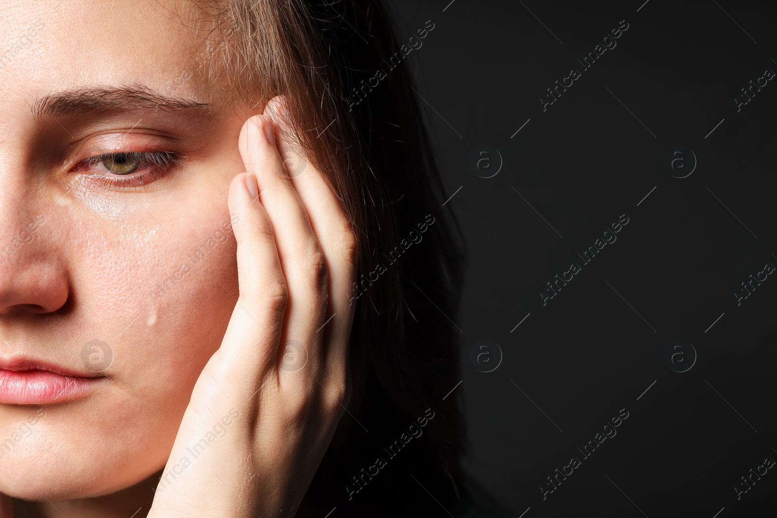 Photo of Sad woman crying on black background, closeup