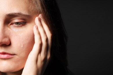 Photo of Sad woman crying on black background, closeup