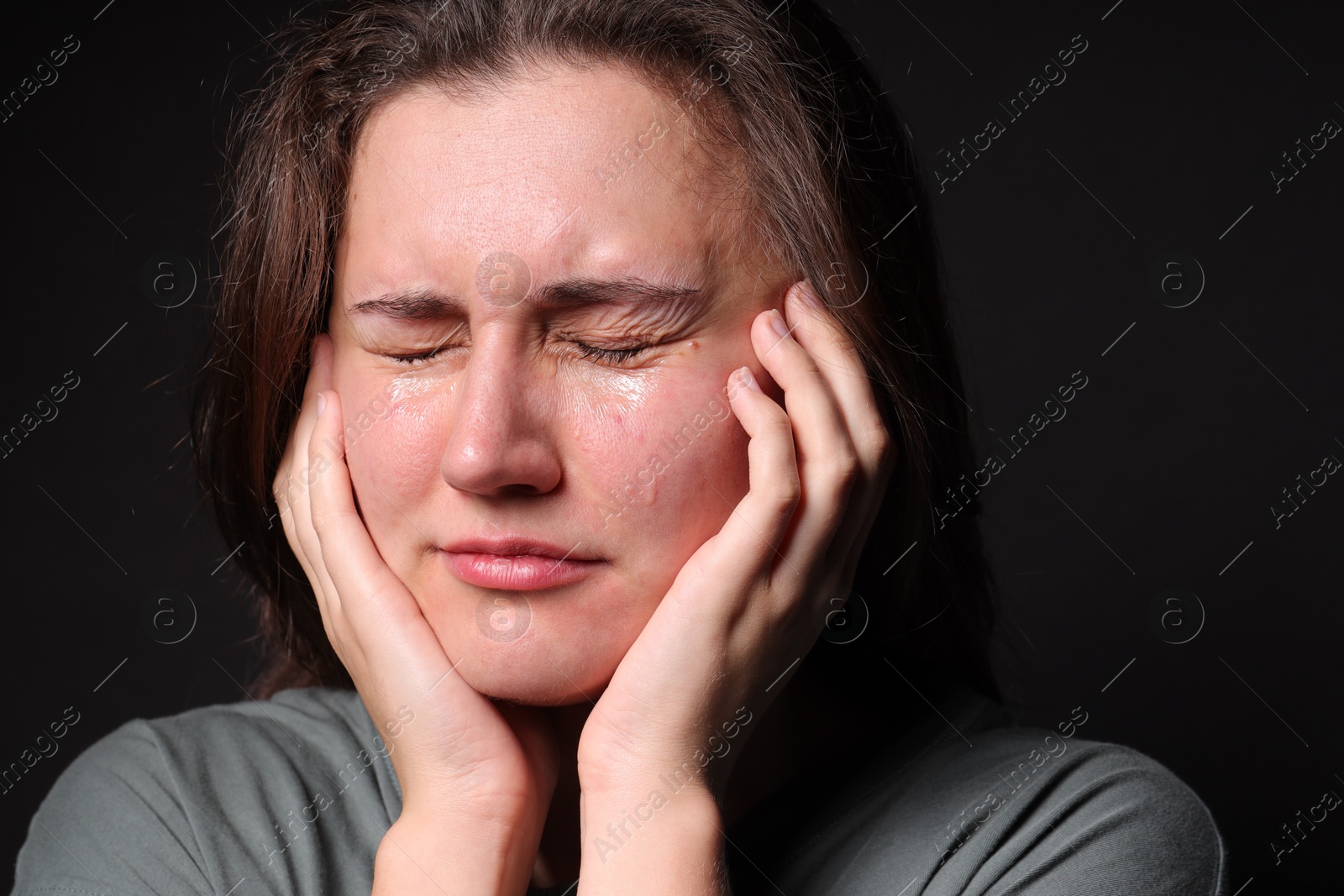 Photo of Sad young woman crying on black background