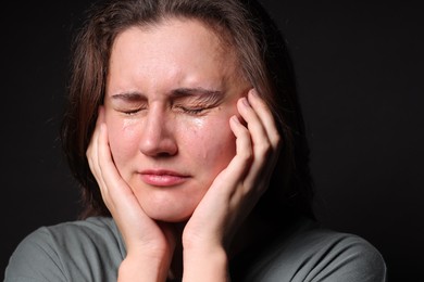 Photo of Sad young woman crying on black background