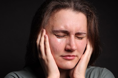 Photo of Sad young woman crying on black background