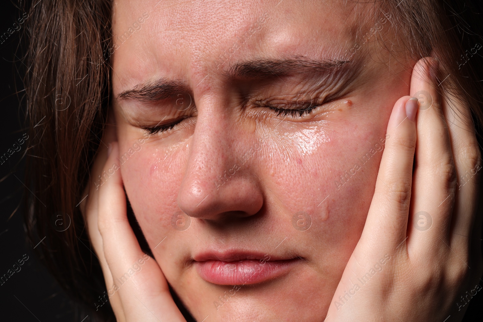 Photo of Sad woman crying on black background, closeup