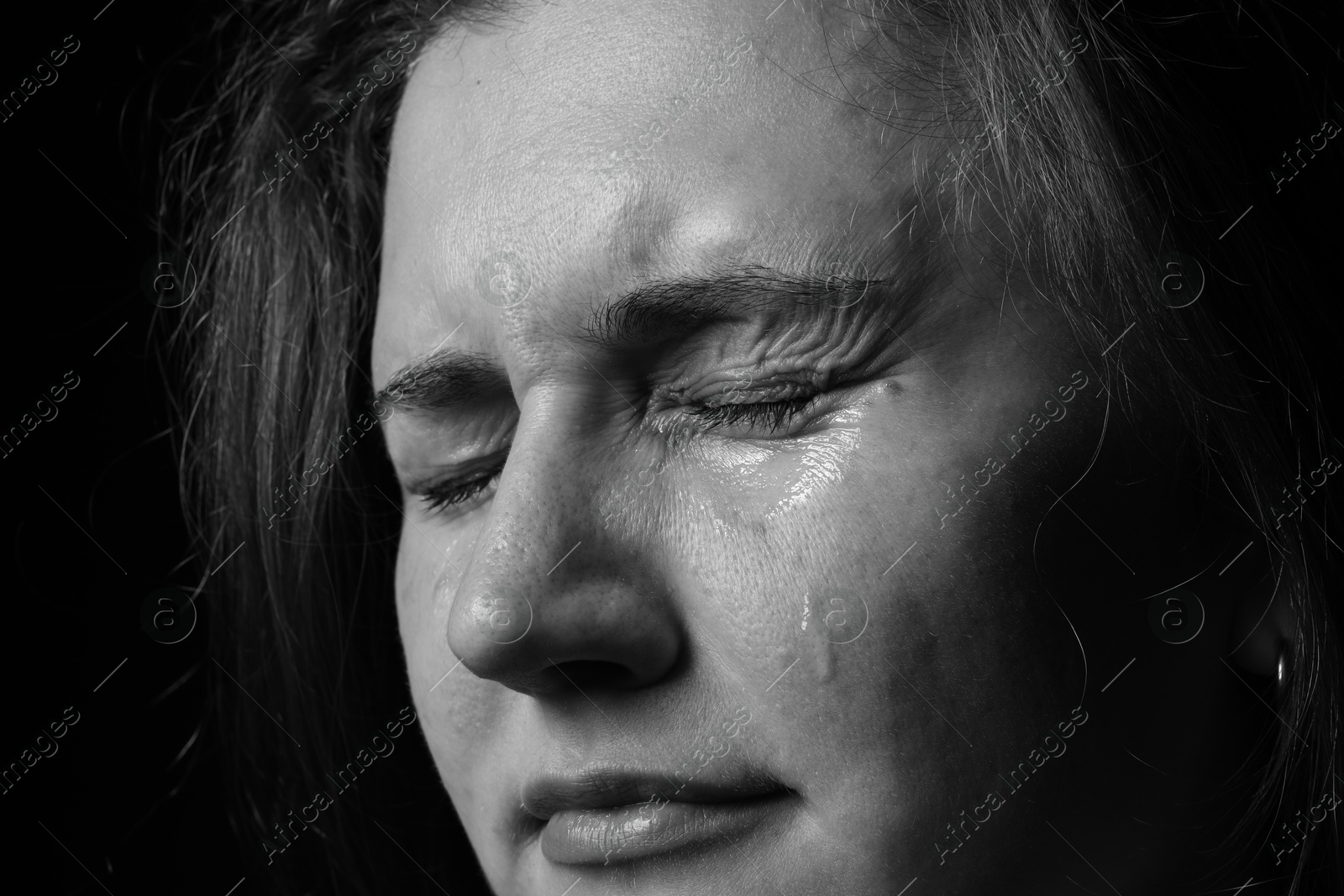 Photo of Sad woman crying on dark background, closeup. Black and white effect