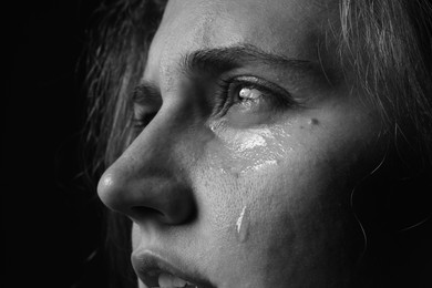 Photo of Sad woman crying on dark background, closeup. Black and white effect