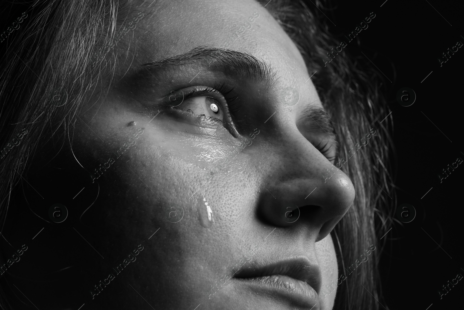 Photo of Sad woman crying on dark background, closeup. Black and white effect