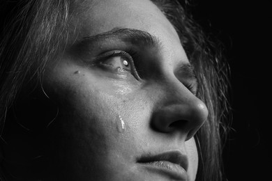 Photo of Sad woman crying on dark background, closeup. Black and white effect