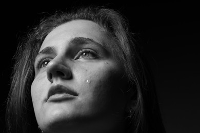 Photo of Sad woman crying on dark background, closeup. Black and white effect