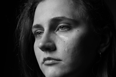 Photo of Sad woman crying on dark background, closeup. Black and white effect