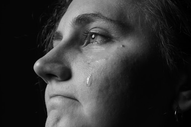 Photo of Sad woman crying on dark background, closeup. Black and white effect