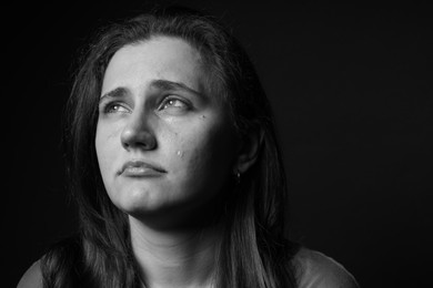 Photo of Sad woman crying on dark background. Black and white effect