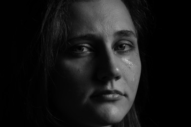 Photo of Sad woman crying on dark background, closeup. Black and white effect
