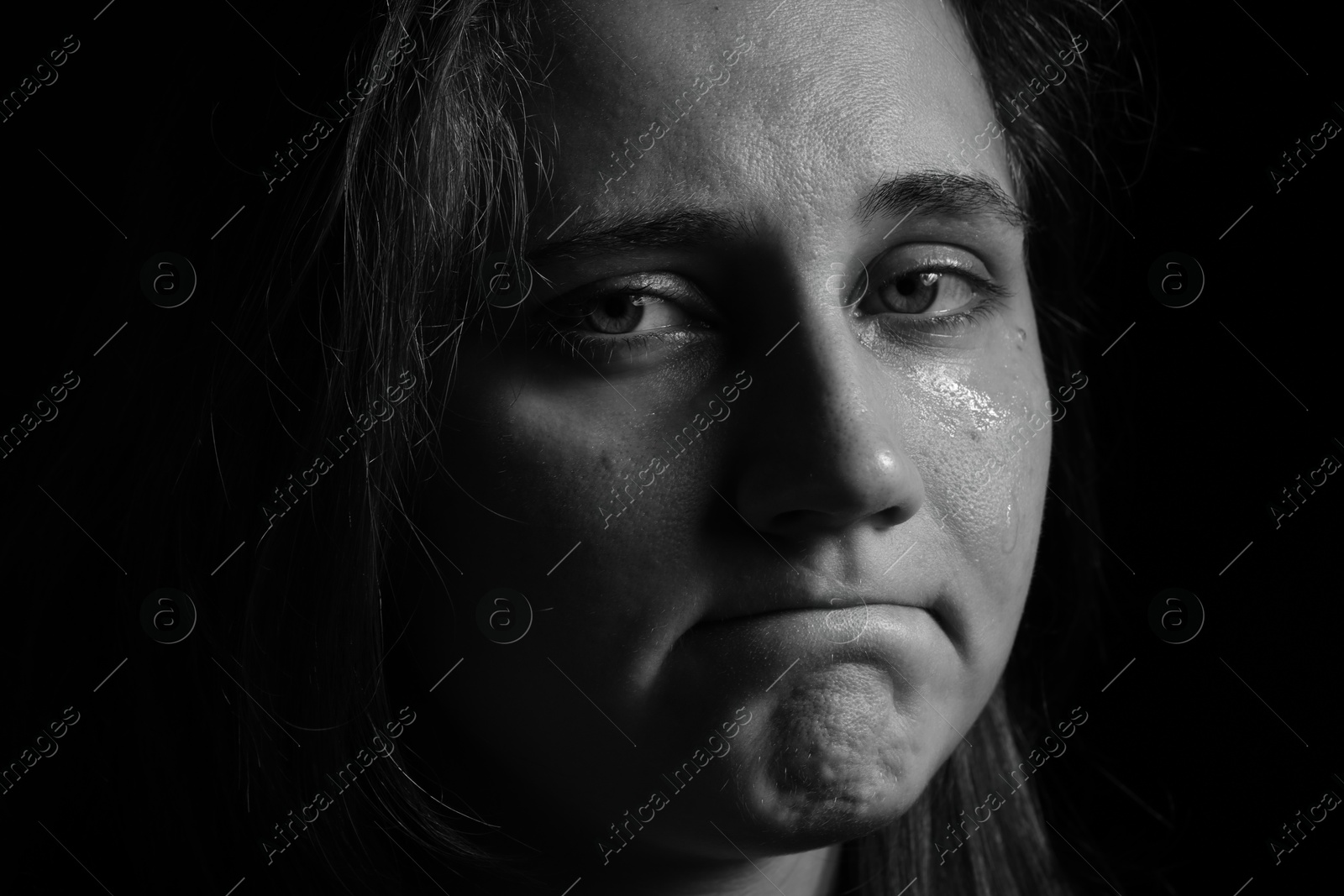 Photo of Sad woman crying on dark background, closeup. Black and white effect
