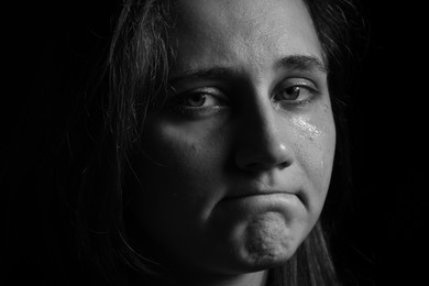 Photo of Sad woman crying on dark background, closeup. Black and white effect