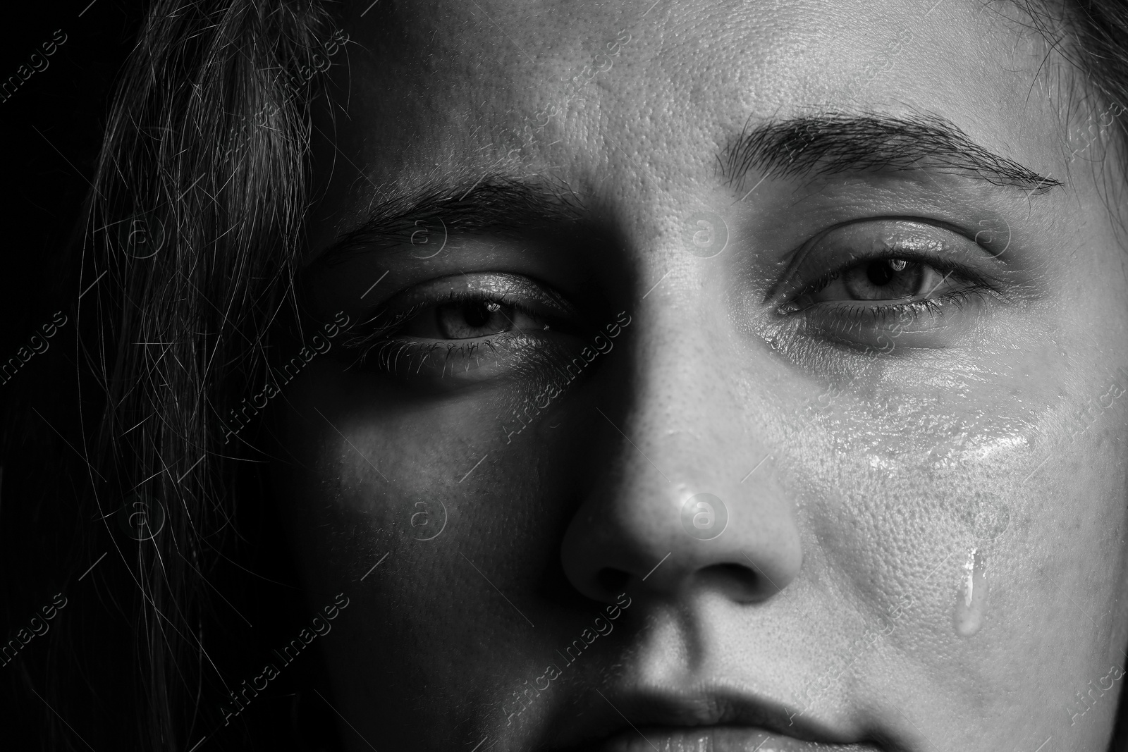 Photo of Sad woman crying on dark background, closeup. Black and white effect