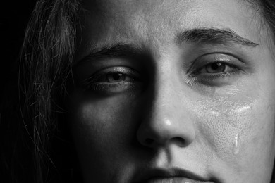 Photo of Sad woman crying on dark background, closeup. Black and white effect