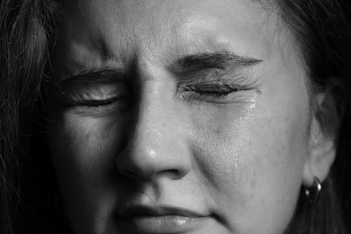 Photo of Closeup view of sad young woman crying. Black and white effect