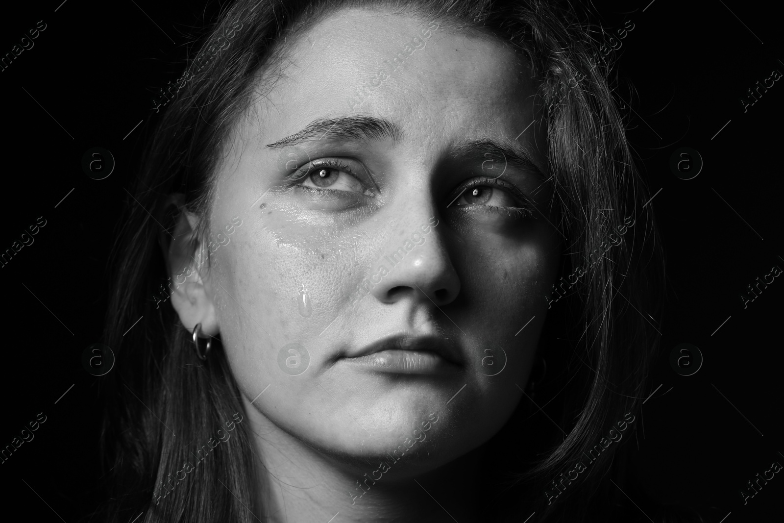 Photo of Sad woman crying on dark background, closeup. Black and white effect