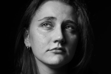 Photo of Sad woman crying on dark background, closeup. Black and white effect