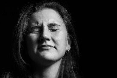 Photo of Sad woman crying on dark background. Black and white effect