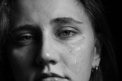 Photo of Sad woman crying on dark background, closeup. Black and white effect