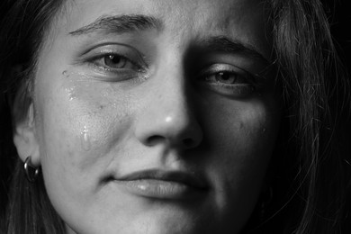 Photo of Sad woman crying on dark background, closeup. Black and white effect