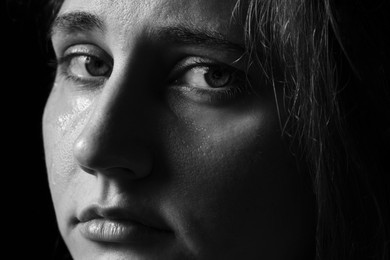 Photo of Sad woman crying on dark background, closeup. Black and white effect