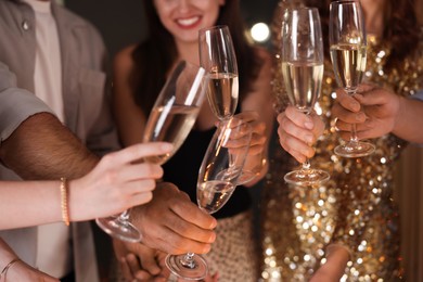 Photo of Friends celebrating New Year with sparklers and wine glasses indoors, closeup