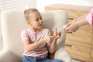 Photo of Mother giving her daughter pocket money at home, closeup